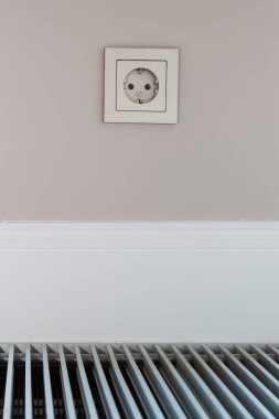 Elektrik prizi beyaz ahşap etek panosunun üstündeki duvara yerleştirildi ve konveksiyon zemine inşa edildi.