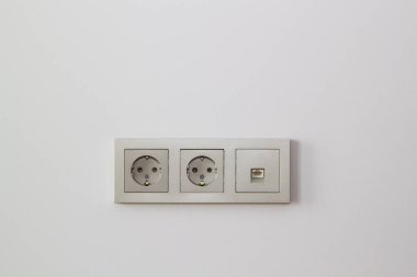 Duvarda elektrik prizleri ve şampanya rengi internet soketi var.