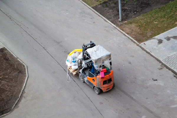 看到一辆叉车把一堆垃圾搬到街上的沥青路面上 — 图库照片