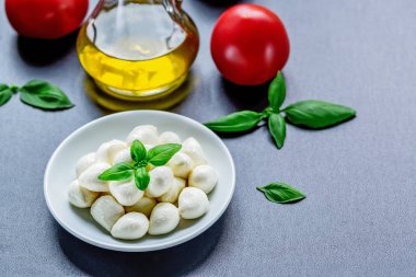 Olgun kırmızı domates, fesleğen yaprakları ve zeytinyağı ile mozzarella peynirli çerez. Caprese salatası için malzemeler