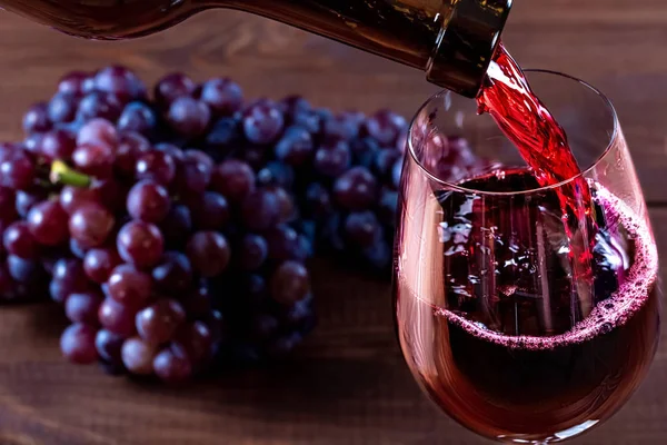 ボトルとグラスの赤ワインや木製の背景にブドウ — ストック写真