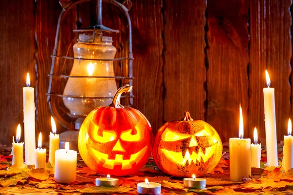 Halloween pumpkins with glowing face on wooden background with candles