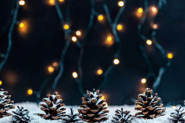 Çam Kozalakları Bokeh Garland Bulanık Bir Arka Plan Üzerinde Karda — Stok fotoğraf