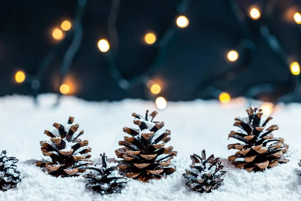 Conos Pino Nieve Sobre Fondo Borroso Guirnalda Bokeh — Foto de Stock