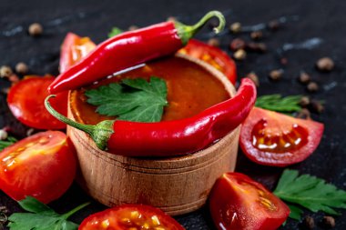 Ketçap taze kiraz domates, biber, baharat ve otlar siyah taş zemin üzerine. Yemek, malzemeler kavramı