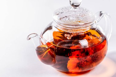 Çiçeklenme büyük çiçekli bir cam demlik çay. Beyaz arka plan üzerinde egzotik yeşil çay çaydanlık