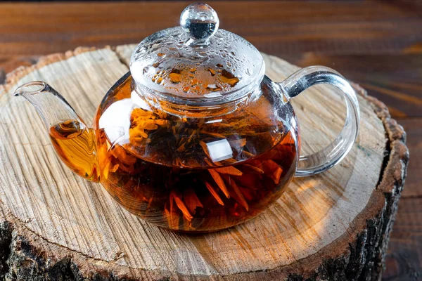 茶在一个玻璃茶壶与盛开的大花 茶壶与异国情调的绿色茶球绽放 木树桩上的茶道 — 图库照片