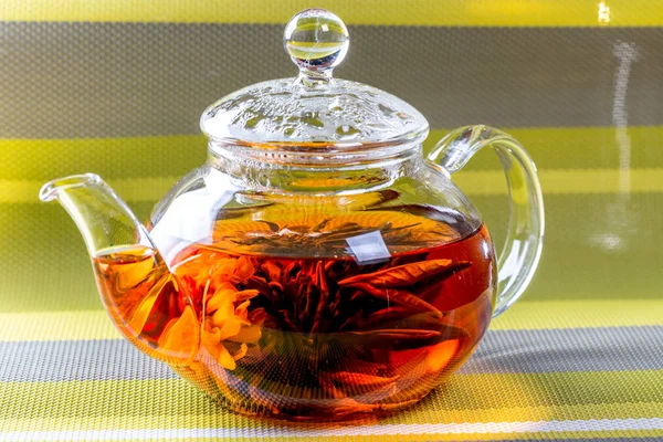 茶在一个玻璃茶壶与盛开的大花 茶壶与异国情调的绿色茶球绽放 在绿色条纹背景的茶道 — 图库照片