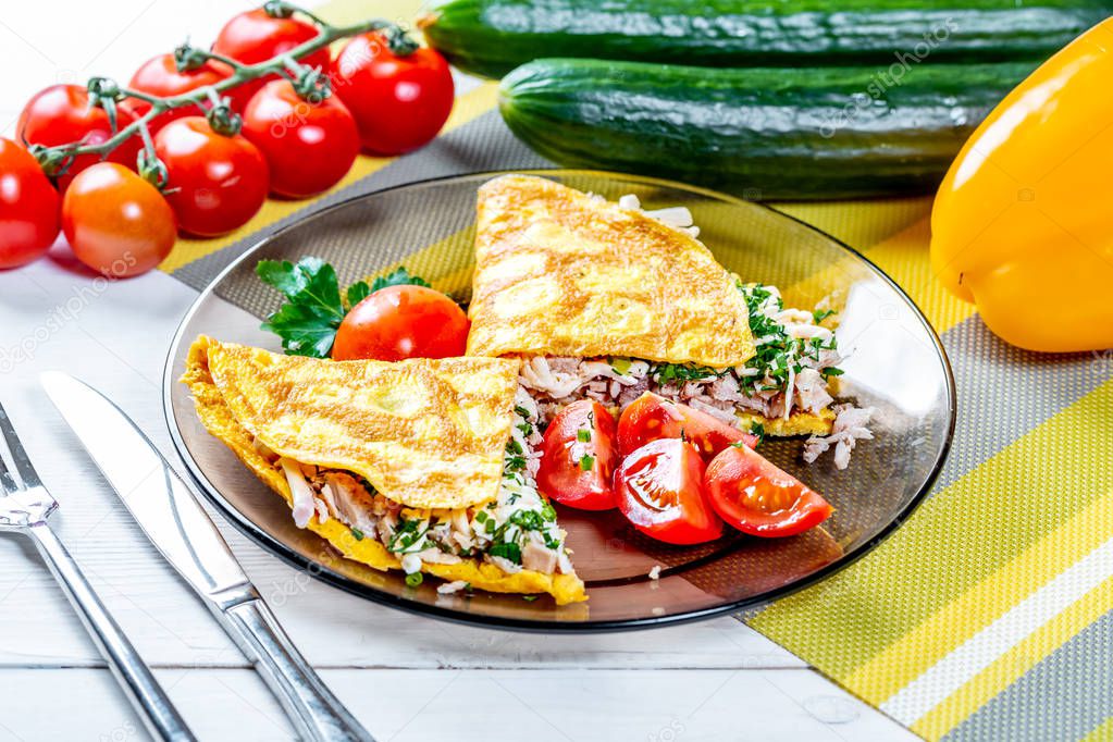 Omelet of chicken eggs stuffed with chicken meat with cheese and herbs. A tasty and healthy Breakfast is served with cherry tomatoes and black olives. The concept of proper nutrition and diet