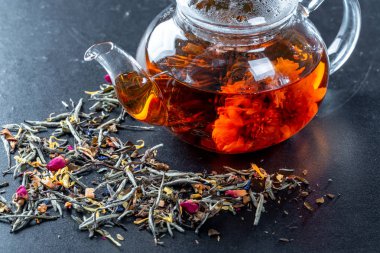 Çiçeklenme büyük çiçekli bir cam demlik çay. Çaydanlık egzotik yeşil çay-topları ile çiçek çiçek açar ve çay ve gül tomurcukları kurutulmuş