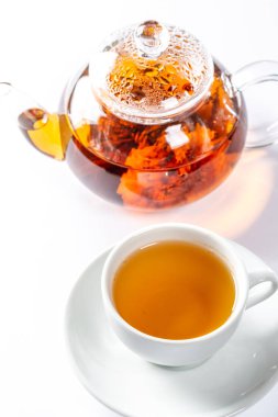 Bir bardak taze çay çiçeklenme büyük çiçekli bir cam demlik çay arkasında bir daire üzerinde. Beyaz arka plan üzerinde egzotik yeşil çay