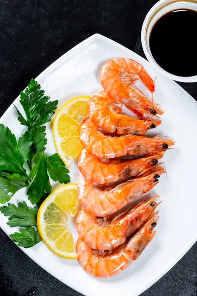 烤虾配酱油、柠檬和香草。皇家美味和美丽的虾在黑色的背景。弗拉特利食物背景 — 图库照片