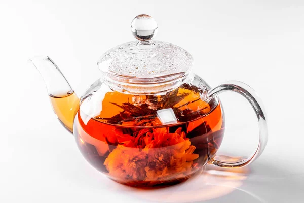 茶在一个玻璃茶壶与盛开的大花。茶壶与异国情调的绿茶在白色背景 — 图库照片