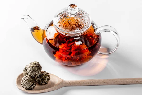 茶在一个玻璃茶壶与盛开的大花。茶壶与异国情调的绿茶在白色背景与干燥的球芽为茶酿造 — 图库照片