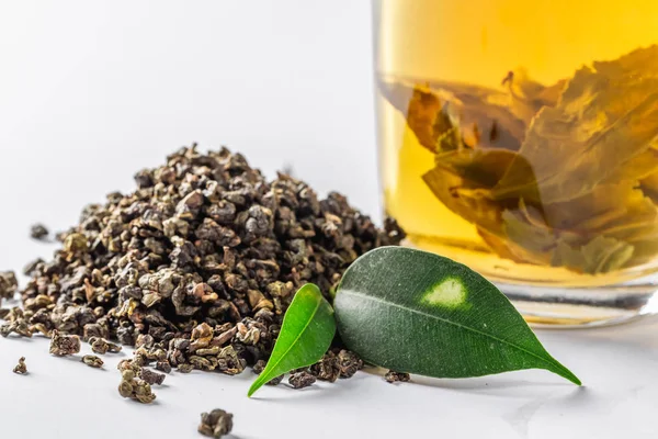 Egy csésze zöld tea és szárított nagy levél friss tea levelek, a fehér háttér előtt. Étrend és egészséges ital — Stock Fotó