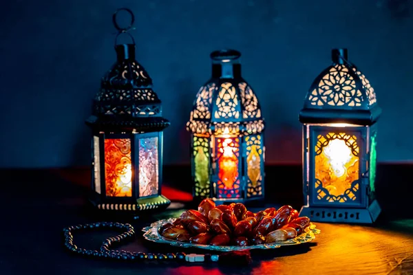 The Muslim feast of the holy month of Ramadan Kareem with dates on a tray on a dark background. Beautiful background with a shining lantern Fanus.