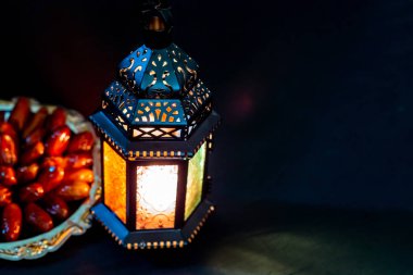 Karanlık bir arka plan üzerinde bir tepsi üzerinde tarihleri ile Ramazan Kareem kutsal ayın Müslüman bayram. Parlayan bir fener Fanus ile güzel bir arka plan. Metniniz için boş alan.