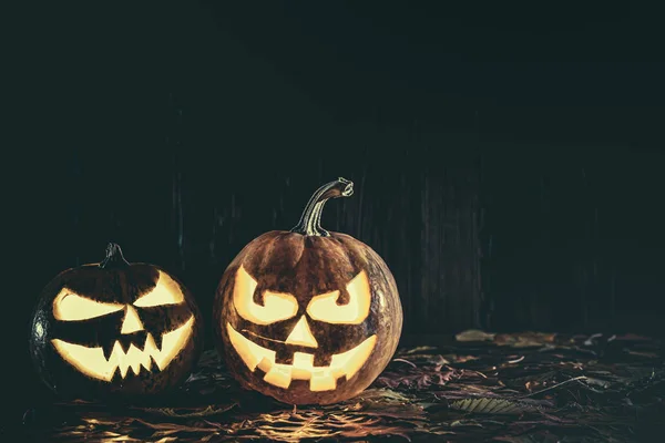 Halloween pompoen met gloeiend gezicht op een houten achtergrond met — Stockfoto