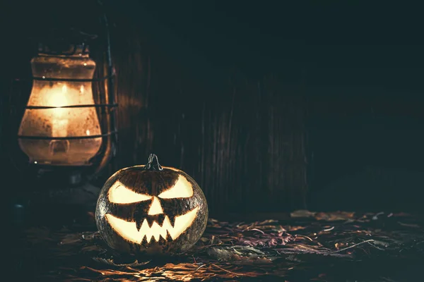 Halloween pumpkin with glowing face on a wooden background with