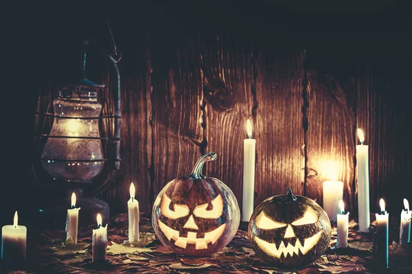 Halloween pumpkin with glowing face on a wooden background with candles