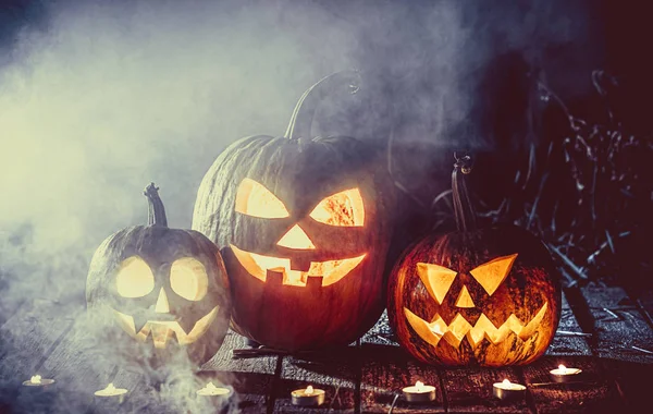 Halloween sütőtök fej jack lantern a gyertyák körül a régi deszkák a kísérteties éjszaka táj. Lágy fókusz. sekély Dof — Stock Fotó