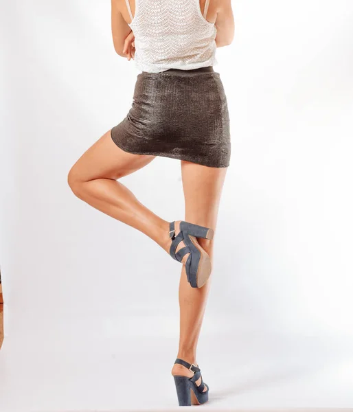 Kvinna bakifrån i svart kjol försöker på skor på grå i studio. — Stockfoto
