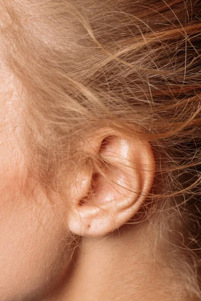 Detail des Kopfes mit weiblichem menschlichen Ohr und blonden Haaren aus nächster Nähe. — Stockfoto