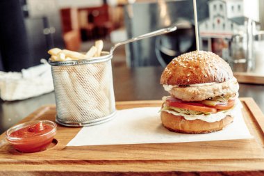 Kağıt bir rustik ahşap plaka üzerinde ızgara tavuk burger sause marul ve domates ile servis