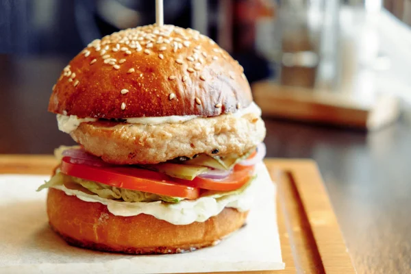 Burger servi sur une planche de bois recouverte de papier — Photo