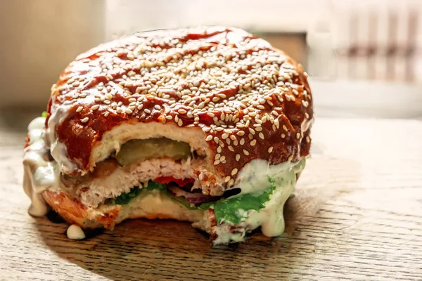 Chutný hamburger na dřevěné pozadí s částí ukousnutý — Stock fotografie