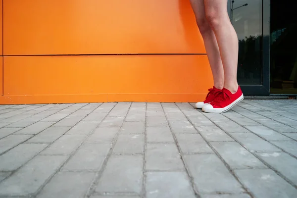 Flickan bär trendiga sneakers. Skor närbild skjuta framför orange vägg — Stockfoto