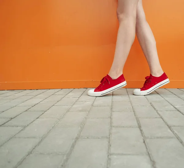 Chica con zapatos rojos de moda. Zapatos de cerca disparar delante de la pared naranja para la tienda de moda —  Fotos de Stock