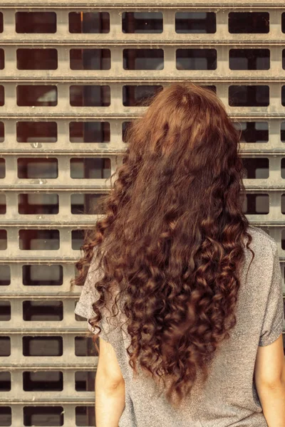 Depressed woman in front of metal grid rear view — Stock Photo, Image