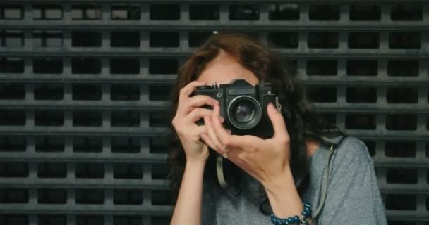 Ευτυχισμένος κορίτσι έφηβος λήψη φωτογραφιών από κάμερα εκλεκτής ποιότητας ταινία μπροστά από μεταλλικό φράχτη — Αρχείο Βίντεο
