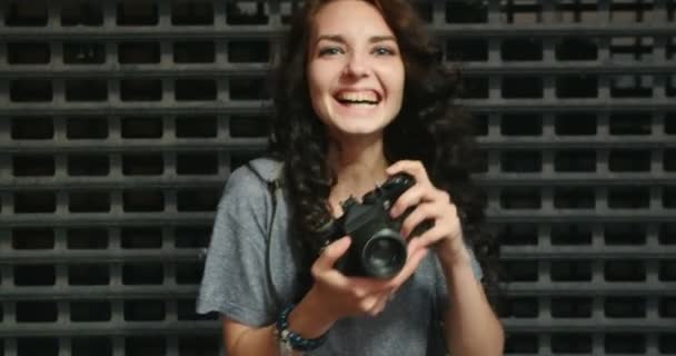 Feliz adolescente chica tomando foto por vintage película cámara en frente de metal rejilla valla — Vídeo de stock