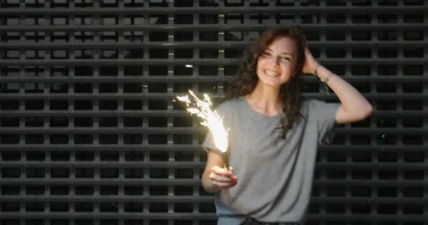 Slow motion beelden van tienermeisje met sparkler in haar handen voor gaas — Stockvideo