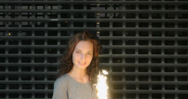 Slow motion footage of teen girl with sparkler in her hands in front of metal grid — Stock Video