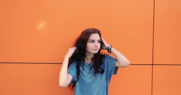 Голова впевненої красивої молодої жінки, на помаранчевому тлі стін. Порожні і позитивні людські емоції вираження обличчя почуття, ставлення, сприйняття — стокове відео