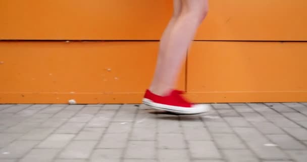 Close up de pernas de uma jovem mulher vestindo tênis vermelho escuro andando — Vídeo de Stock