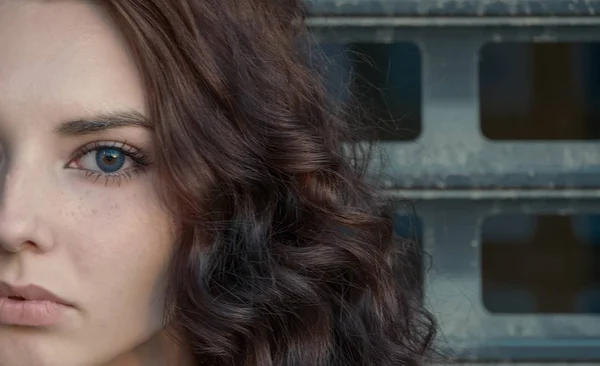 Broody girl half face in front of metal grid looking at camera — Stock Photo, Image