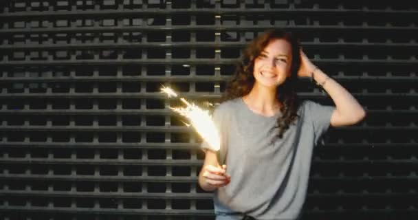 Outdoor photo of young beautiful happy smiling girl holding sparklers posing in night street. — Stock Video