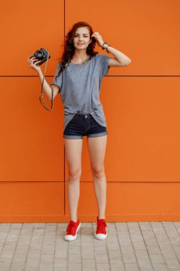 Hipster teen turuncu duvar, kopya alanı, önünde bir el ayakta vintage fotoğraf makinesi ile görüntü tonda