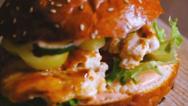 Hambúrguer saboroso com carne de frango frita pepino de cebola e alface girando em câmera lenta — Vídeo de Stock