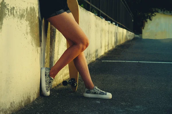 Elegantes piernas delgadas de patinadora de longboard femenina en skate park una gran cantidad de copyspace . — Foto de Stock