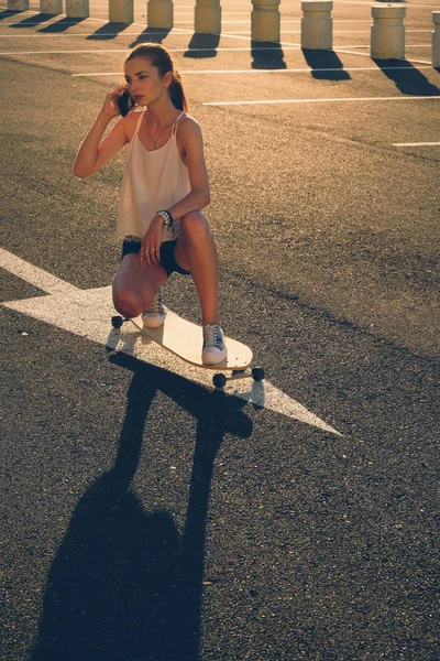 Γυναίκα για skateboard μιλάμε στο τηλέφωνο σε ηλιόλουστη μέρα — Φωτογραφία Αρχείου