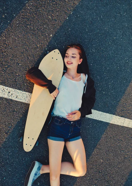 Skater flicka liggande på asfaltens yta av väg- och ordnade varma sommarvädret efter fysisk aktivitet — Stockfoto