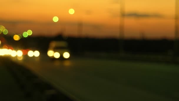 Carretera nocturna con faros de coches borrosos y cielo naranja al atardecer — Vídeo de stock