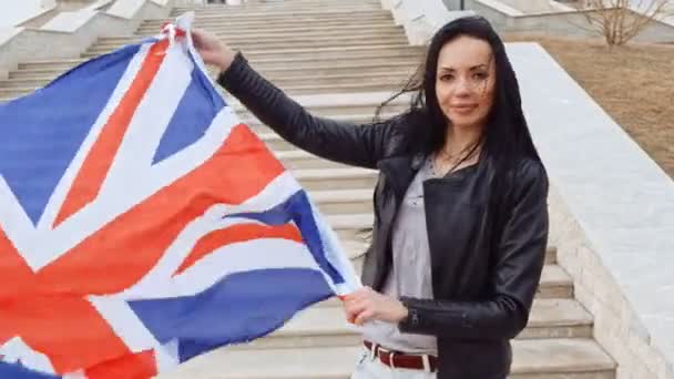 Black haired woman holding in hands Union Jack Flag Waving On Wind