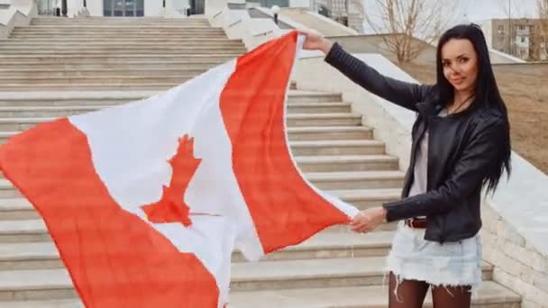 Активіст Latino дівчина з розмахував прапором нації Канади в руки, дивлячись на камеру і посміхаючись Fhd кадри — стокове відео