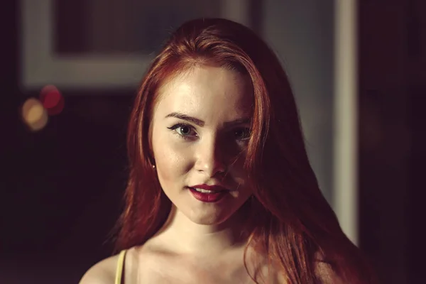 Ginger haired girl, portrait in night city setting. Street fashion style portrait of young pretty woman with long red hair